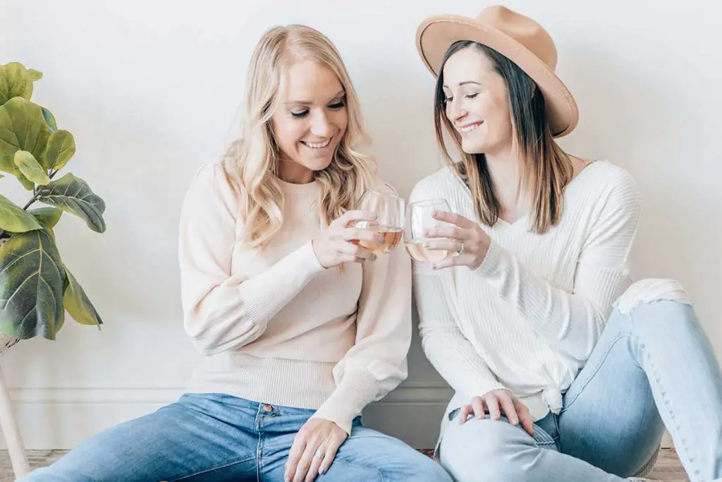 Two girls holding and clinking glasses