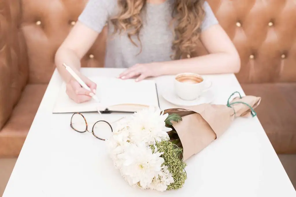 Woman writing next to bouquet of flowers