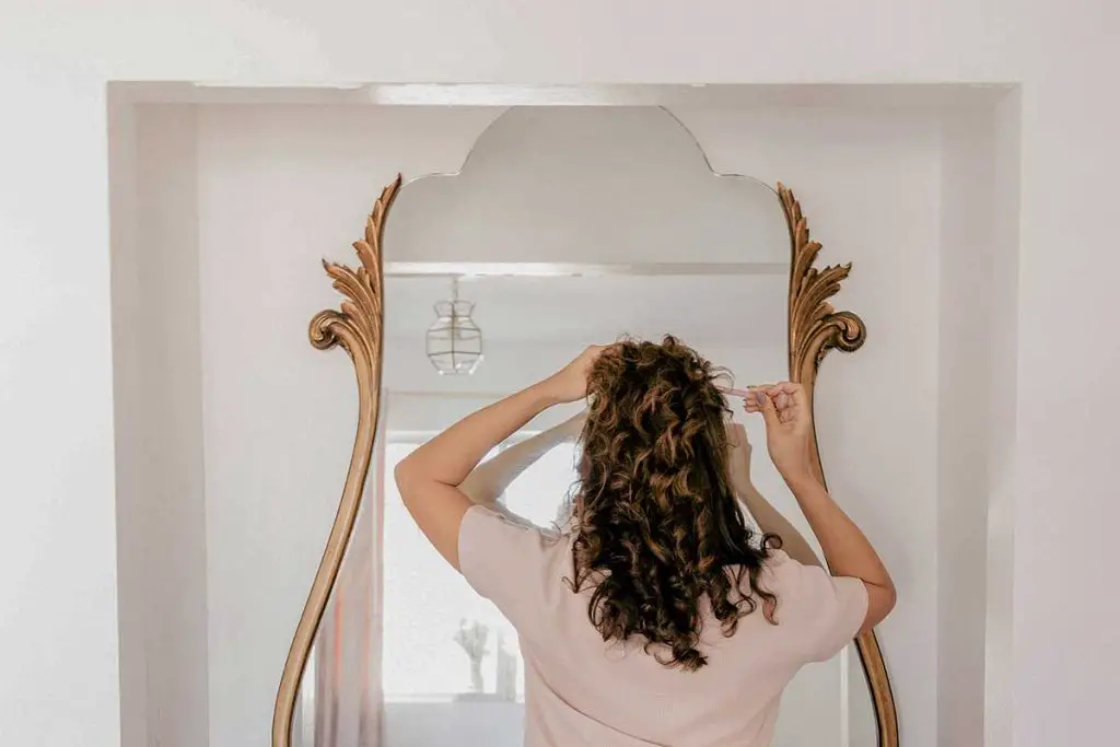 Woman doing her hair in front of the mirror