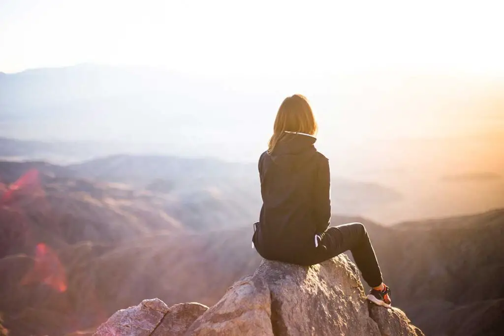 Girl sitting on rock looking out at nature