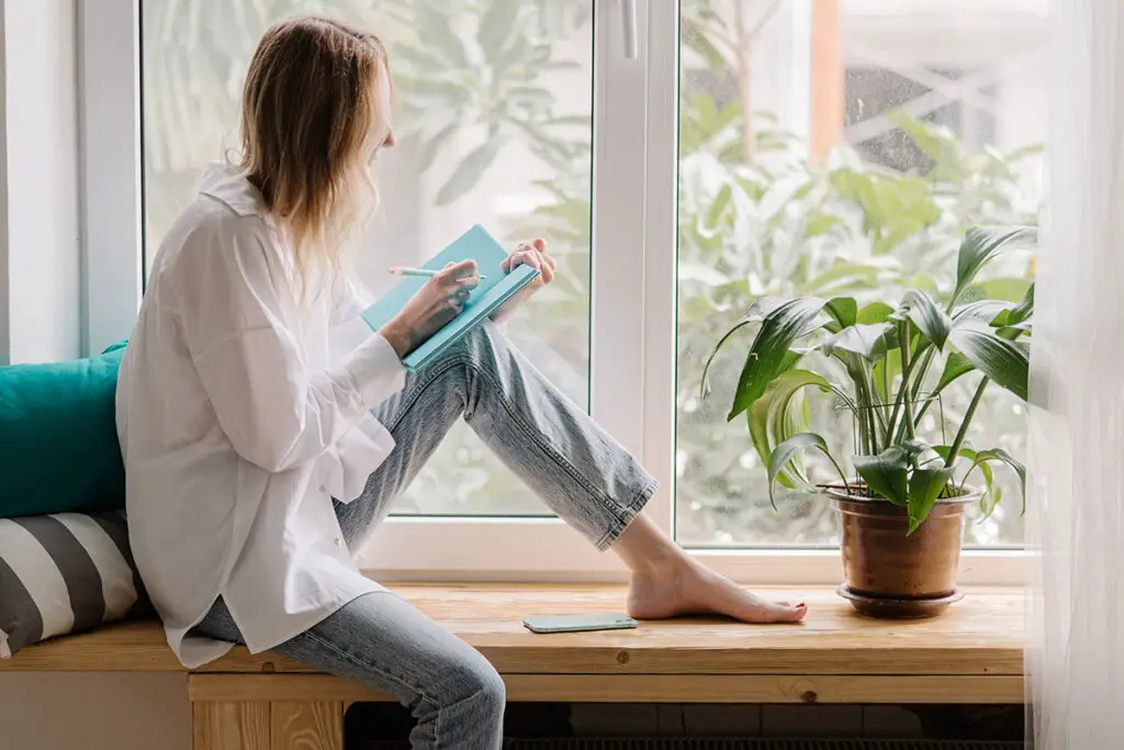 Woman journaling in front of window