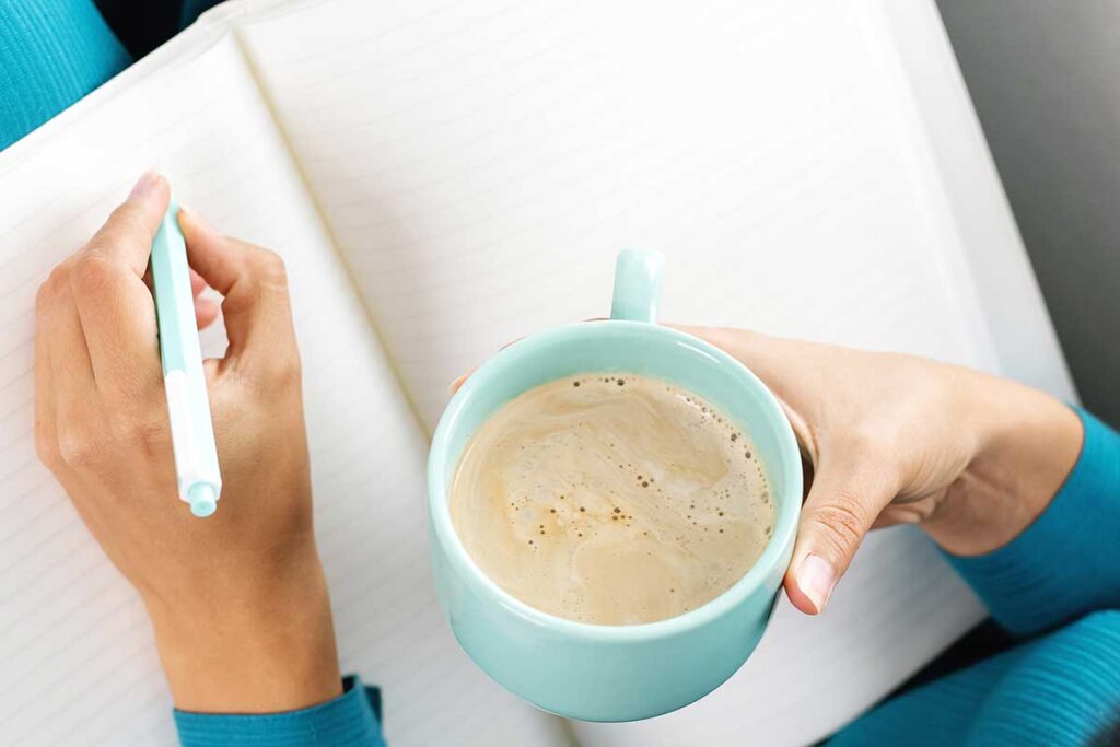 Woman drinking coffee and writing