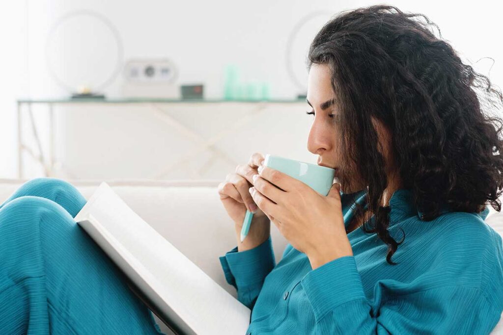 Woman sipping from mug and journaling