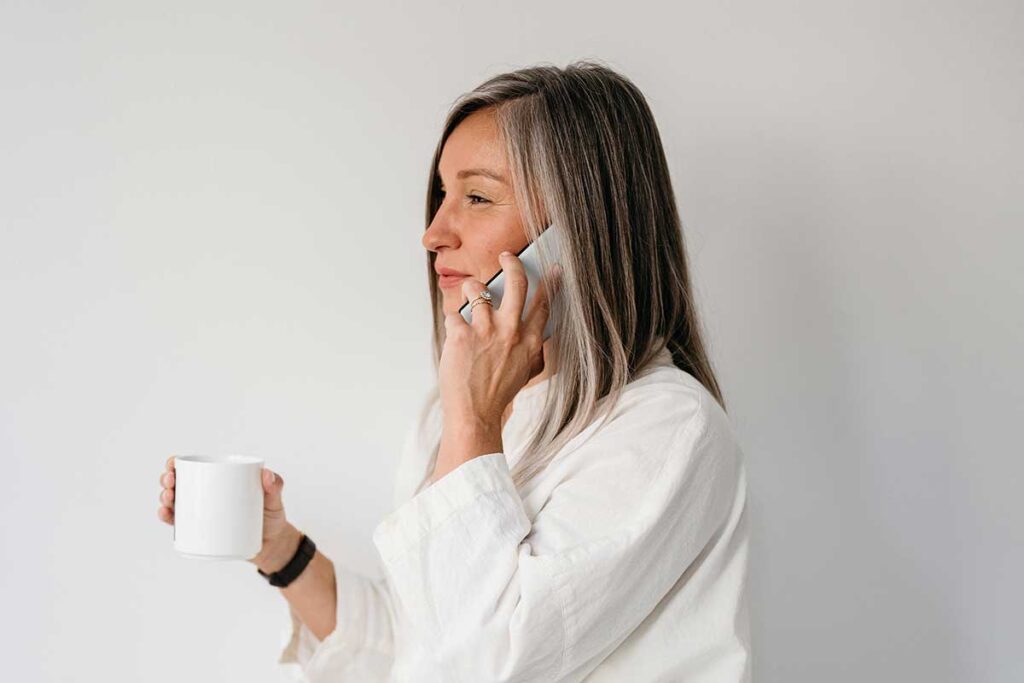 Woman on cellphone holding coffee mug