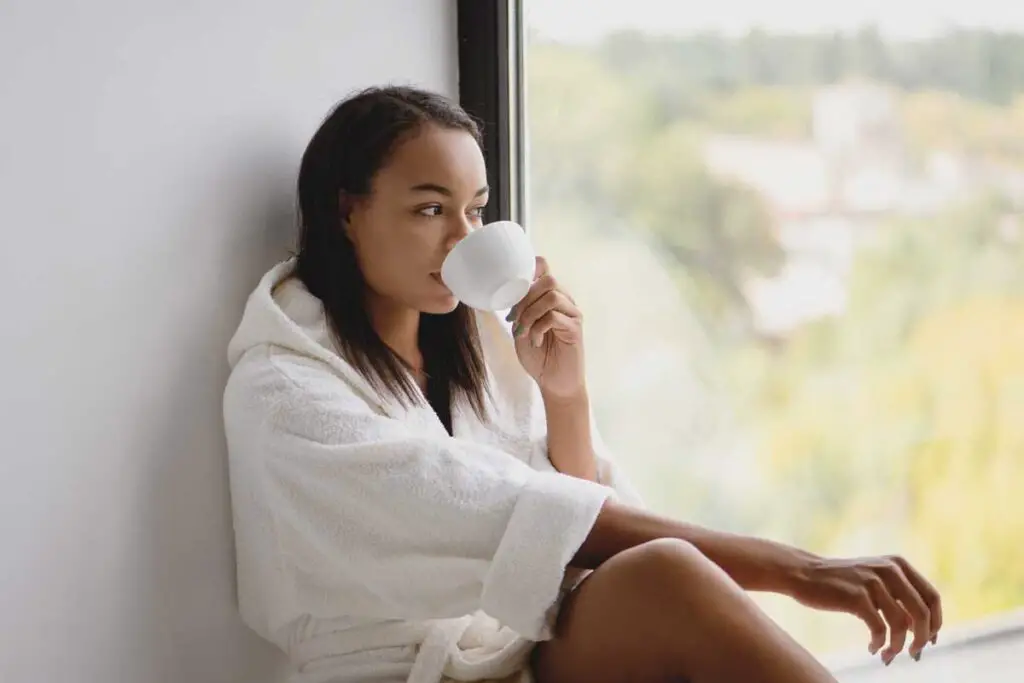 Woman drinking from tea cup in window